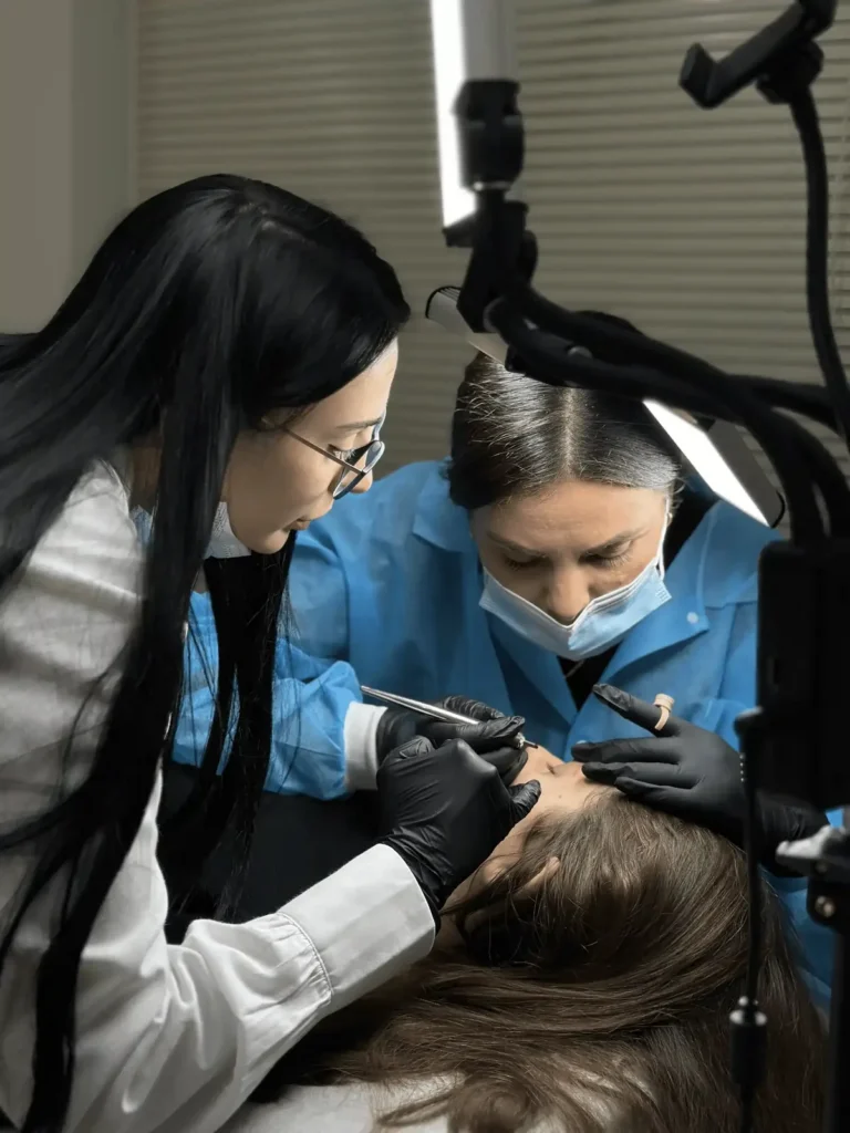 Martina Cetaj guiding a student who is practising permanent makeup on a model