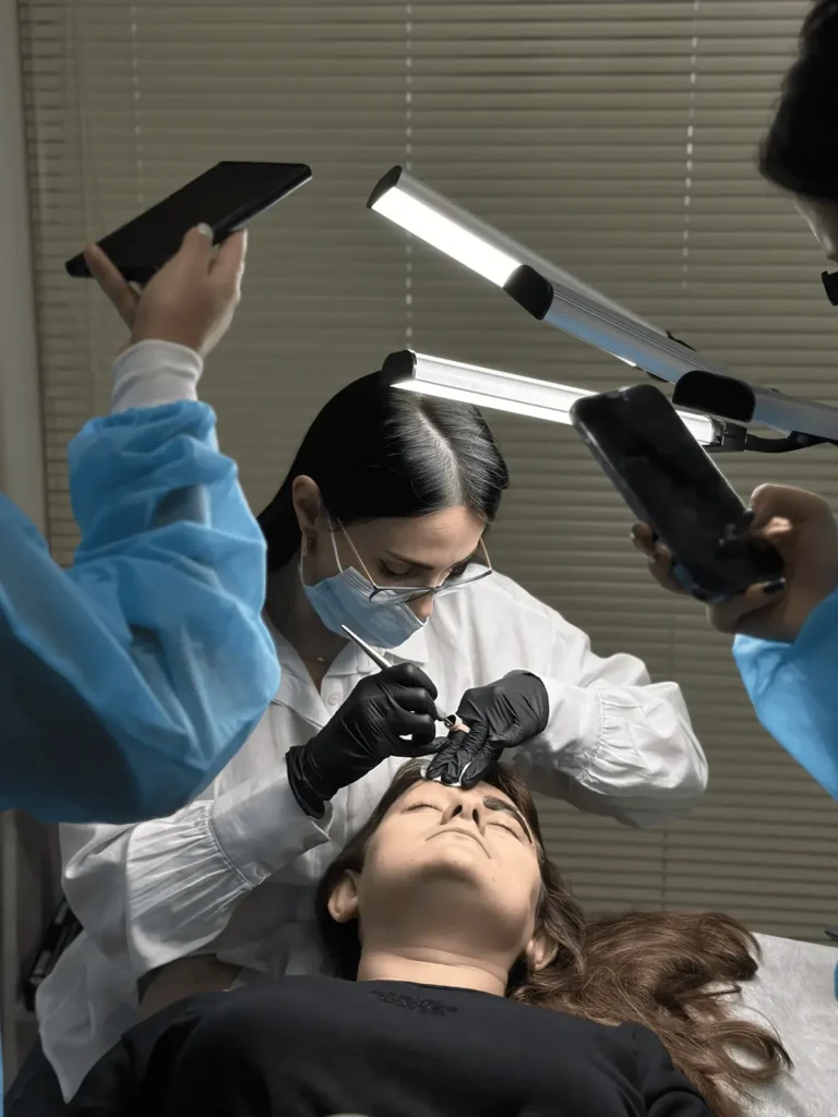Martina Cetaj performing a permanent makeup demonstration while students record and watch